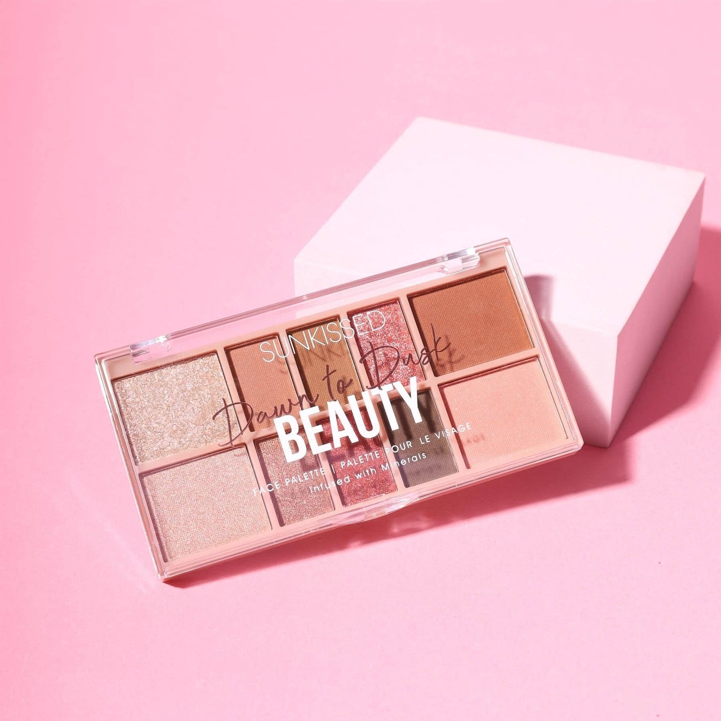 A six-shade makeup palette from Sunkissed Beauty, titled 'Draw for Dust', displayed on a pink background next to its light pink packaging box.