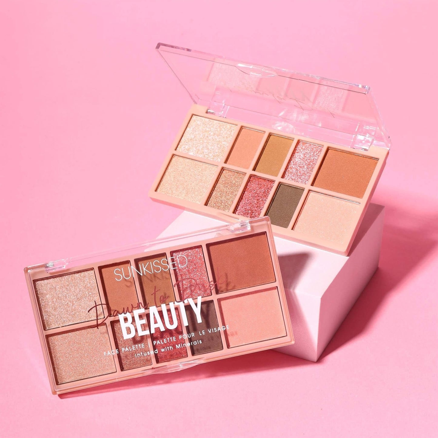 Two Sunkisied Beauty eyeshadow palettes in a pink color theme, one open and one closed, displayed on a pink background with a white block.