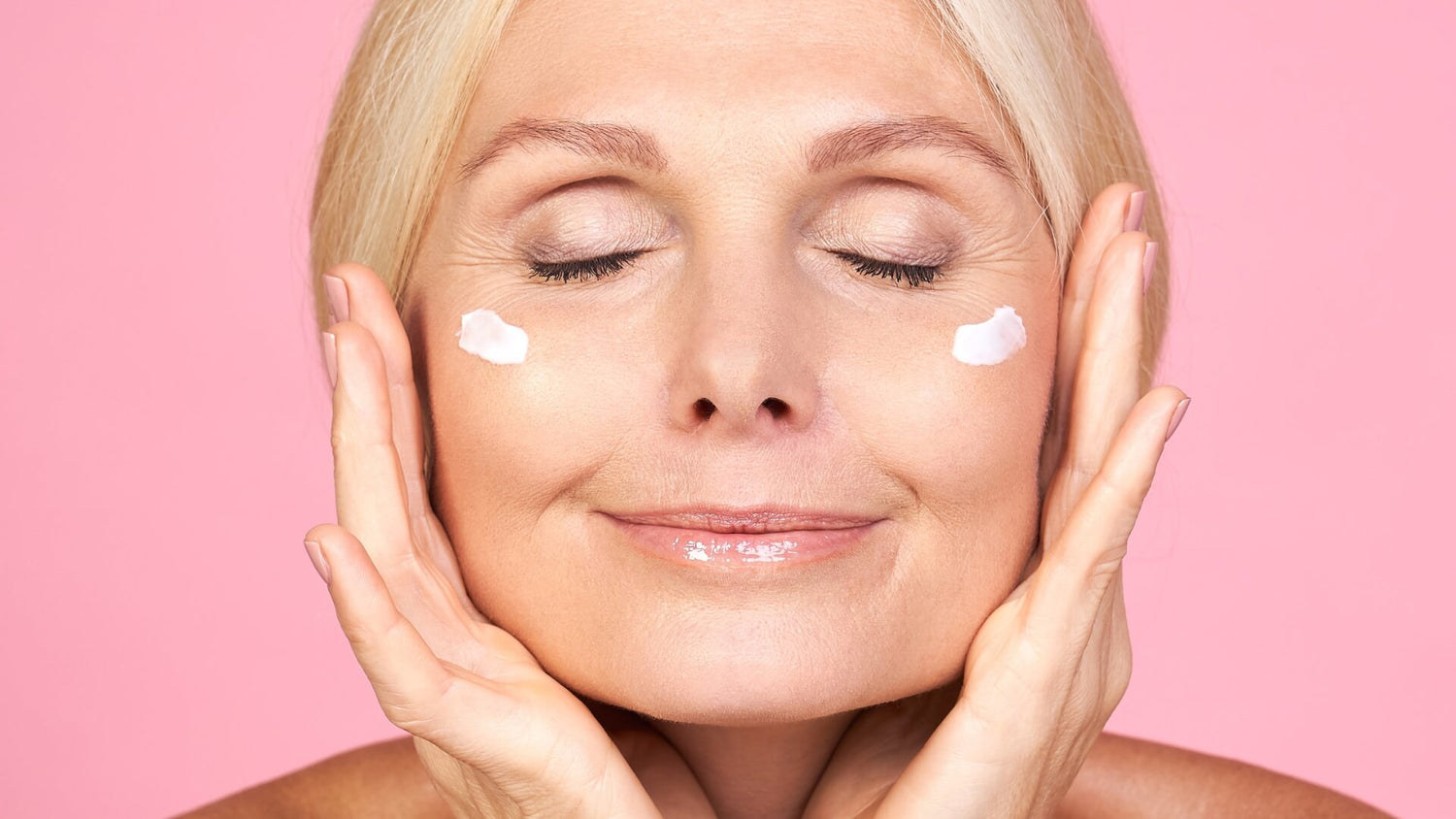 Mature woman with glowing skin applying face cream for a radiant skincare collection homepage banner