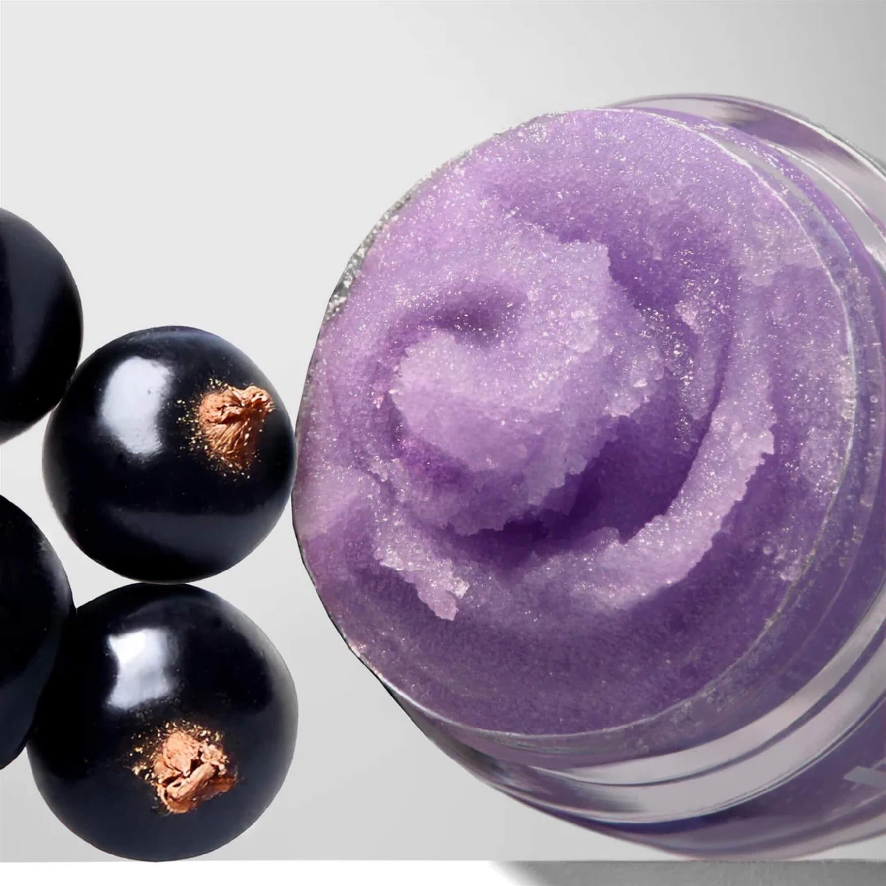 Close-up of Barry M Blackcurrant Soufflé Lip Scrub showing the swirled purple sugary texture next to fresh blackcurrants