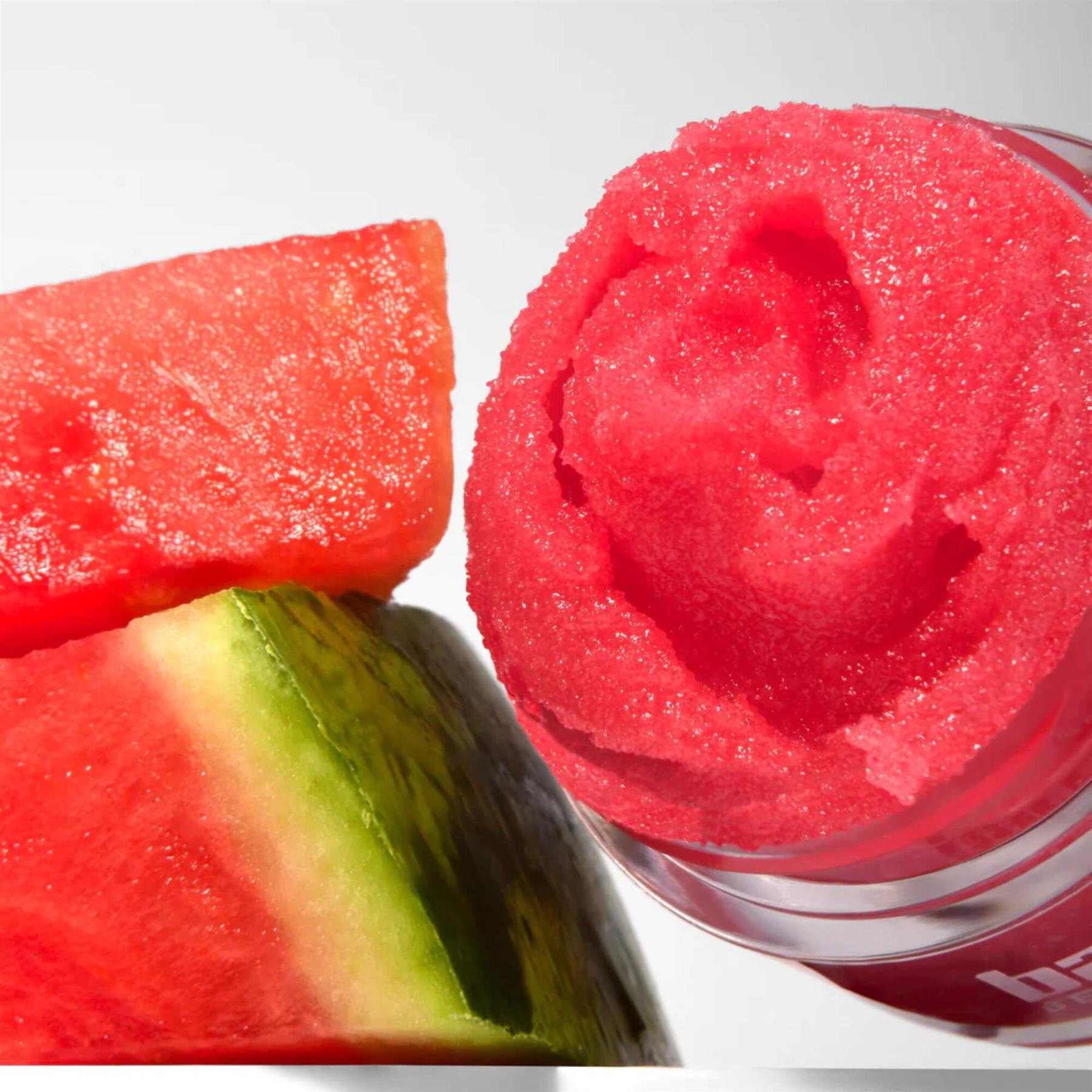 Close-up of Barry M Watermelon Soufflé Lip Scrub showing the swirled red sugary texture next to fresh watermelon slices