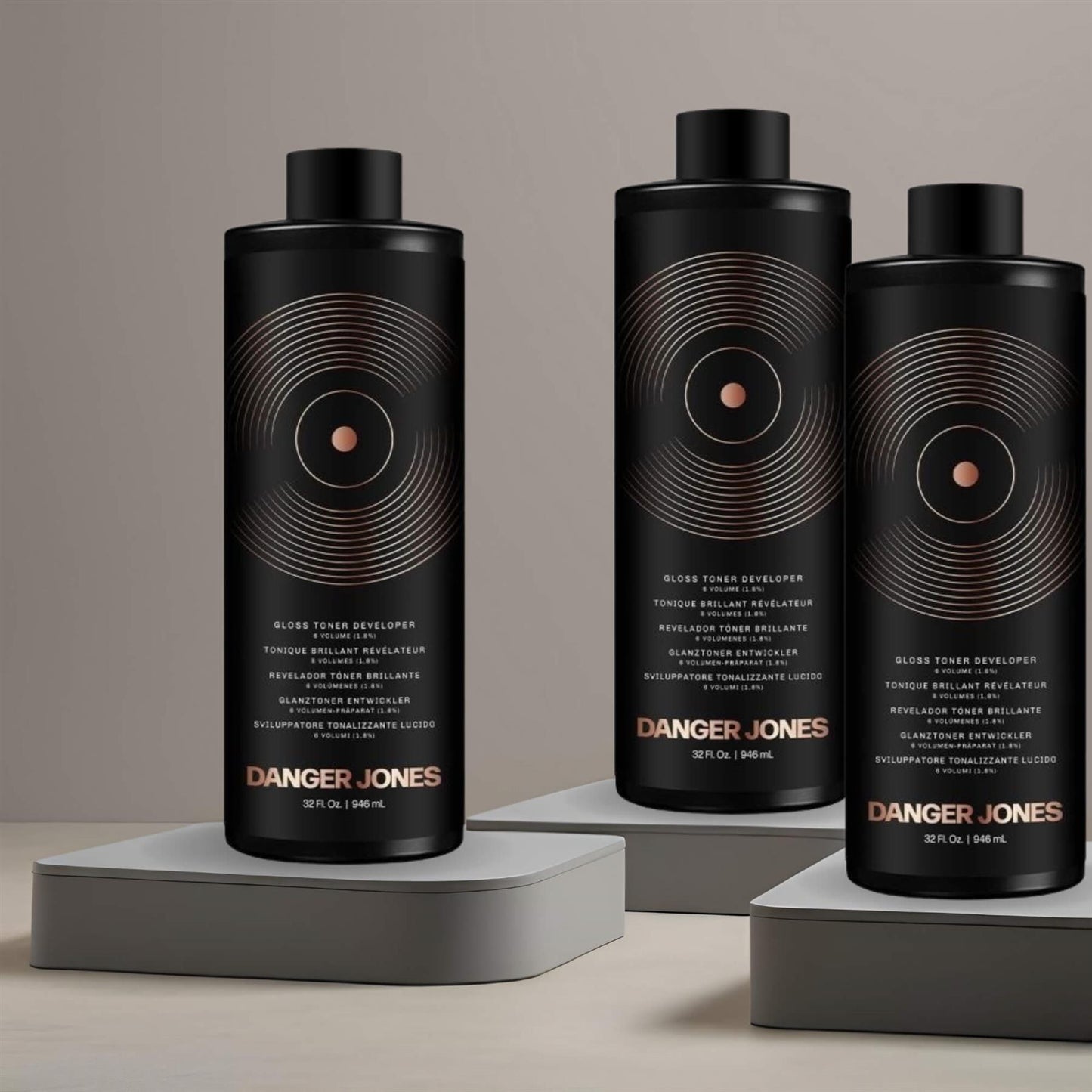Three bottles of Danger Jones Gloss Toner Developer 946ml 6 Volume 1.8% on grey display stands for professional salon use