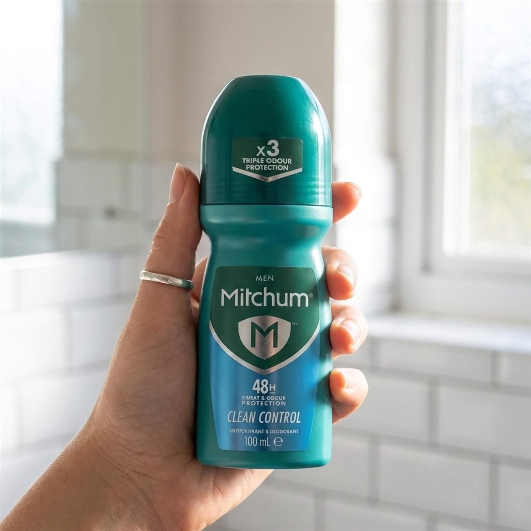 Hand holding Mitchum Men Clean Control 48H roll-on 100ml in bathroom