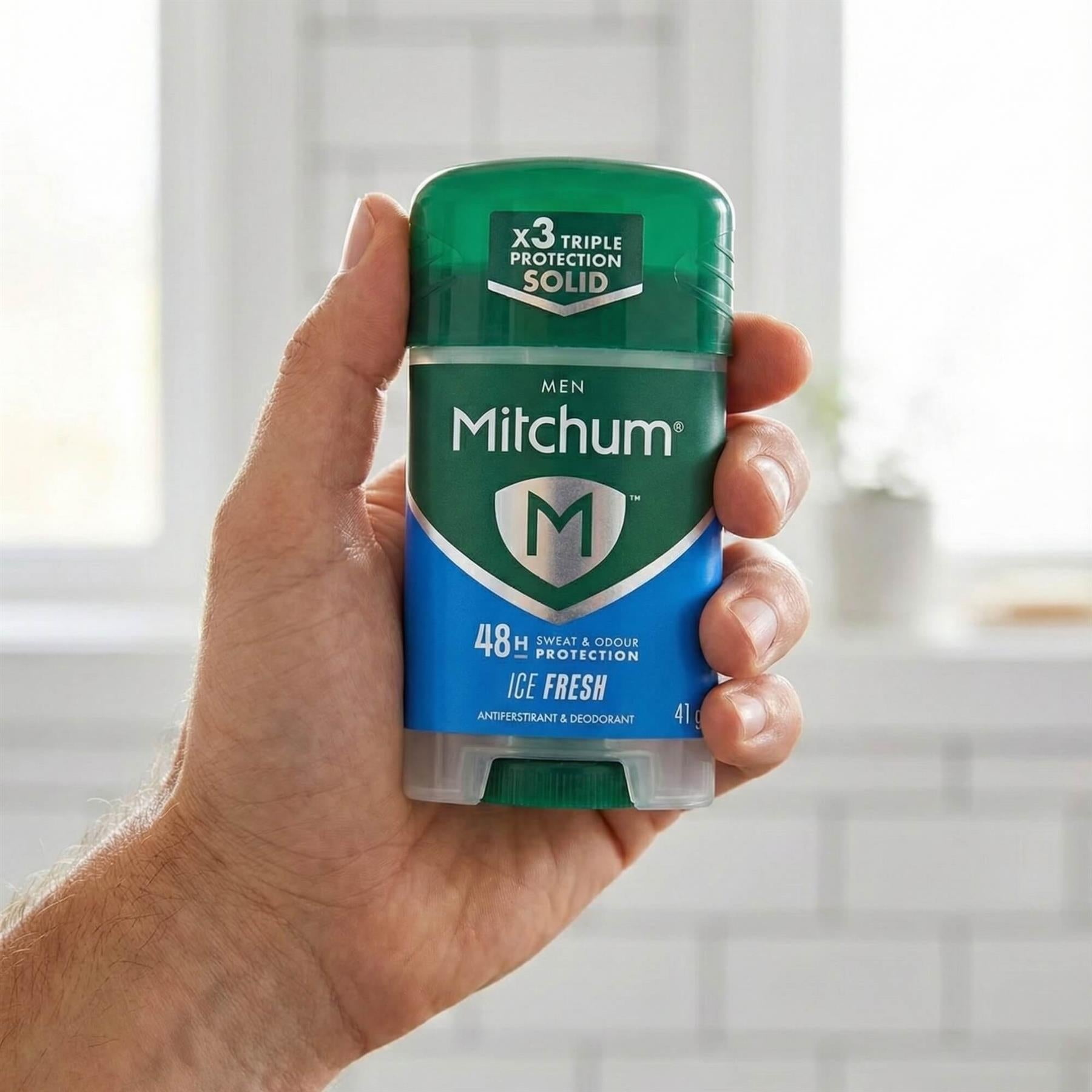 Hand holding Mitchum Men Ice Fresh 48H antiperspirant solid stick in bathroom