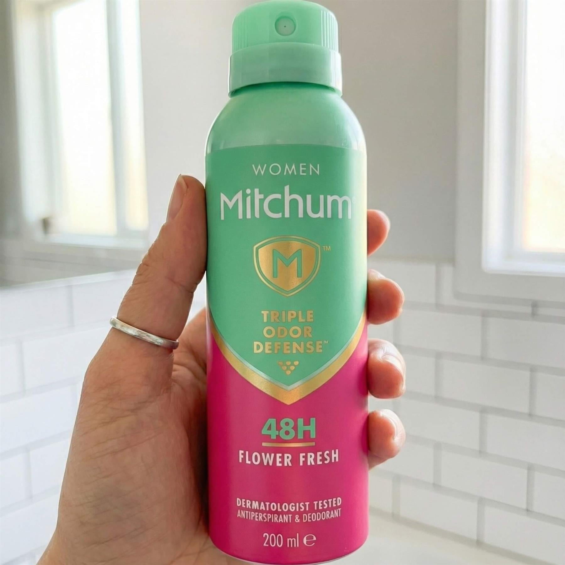 Hand holding Mitchum Women Flower Fresh 48H Triple Odour Defense antiperspirant spray in bathroom
