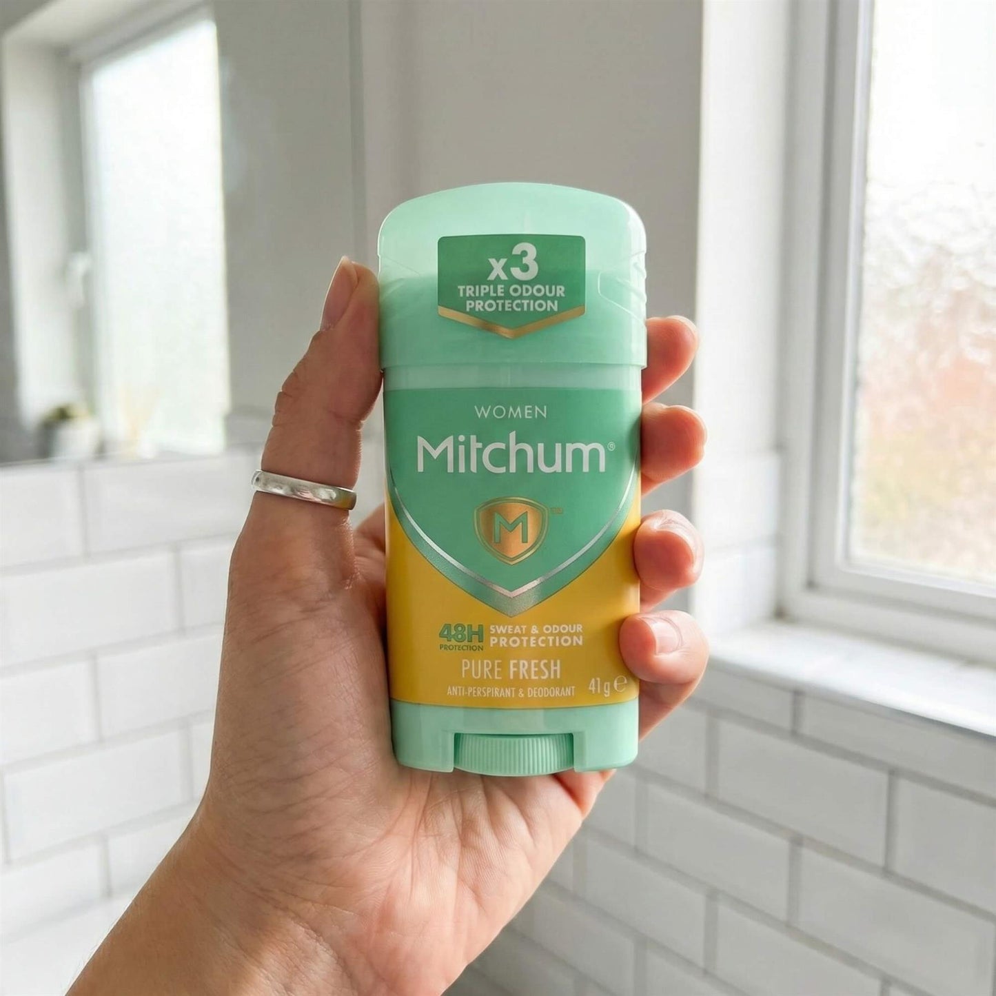 Hand holding Mitchum Women Pure Fresh 48H Triple Odour Protection antiperspirant solid stick in bathroom