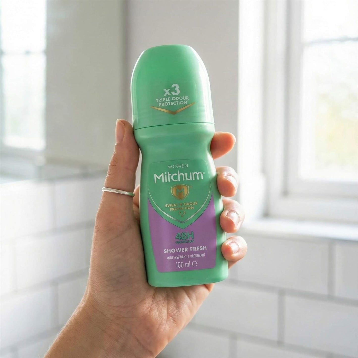 Hand holding Mitchum Women Shower Fresh 48H Triple Odour Protection roll-on in bathroom