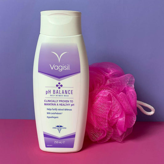 Vagisil pH Balance Daily Intimate Wash 250ml bottle with LactoPrebiotic next to a pink shower loofah