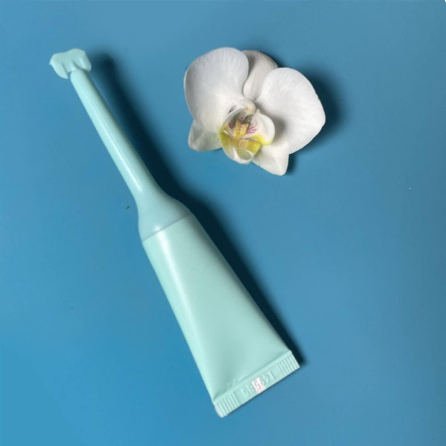 Single Vagisil ProHydrate Internal Moisturising Gel applicator on a blue background with a white orchid flower