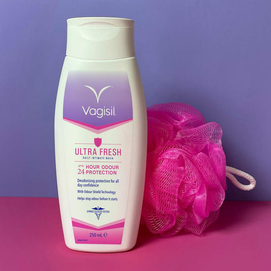 Vagisil Ultra Fresh Daily Intimate Wash 250ml with Odour Shield Technology next to a pink shower loofah